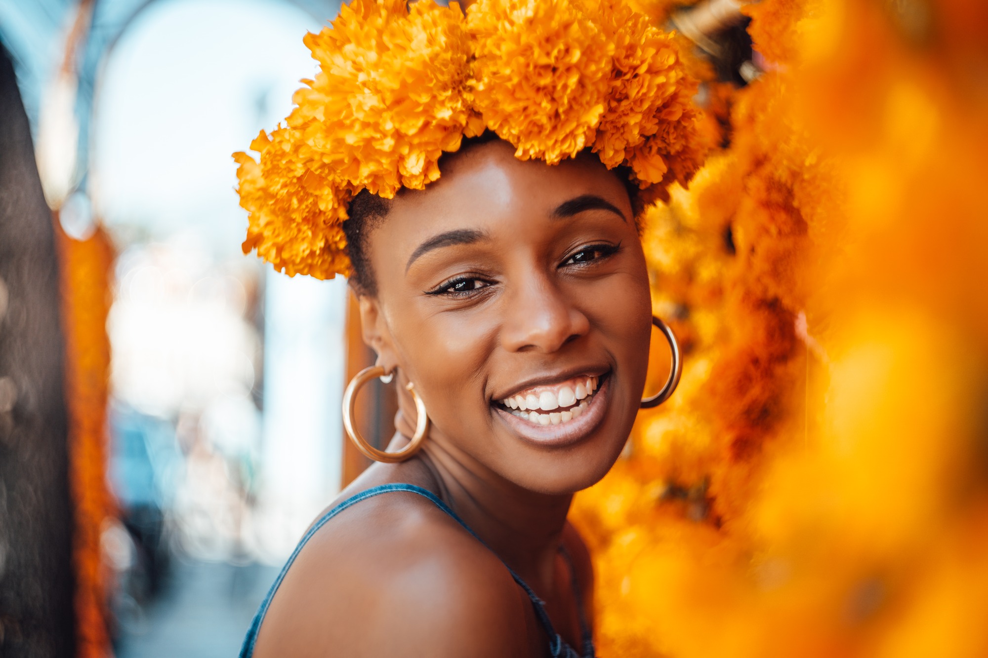 Smiling woman wearing a marigold flower crown, orange blooms filling the frame