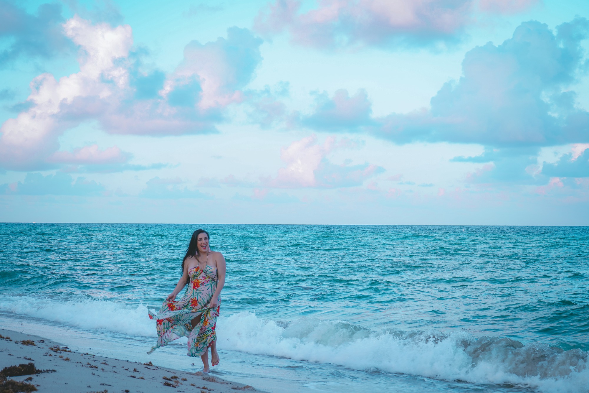 Woman in a long dress standing in the shallow turquoise surf